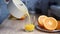 Woman\\\'s hand pours freshly squeezed orange juice into a glass