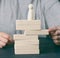 Woman`s hand pulls out a wooden block from the tower on which the figurine stands. The concept of reputational risks