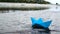 Woman`s hand putting blue paper boat on the water and pushing it away