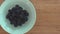 A woman`s hand putting a bowl full of blackberries on a cutting board, removing them again.