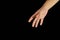 A woman`s hand reaches out from a top corner. Isolated women open palms on a black background. Concept of helping hand, relations,
