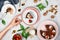 Woman`s hand reaching for a piece of vegan chocolate cake surrounded by walnuts, strawberries, cocoa powder and other dessert ing