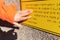 A woman`s hand reads a yellow Braille sign. Close up. Concept of the day of the blind and disability