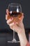 Woman`s hand with red nails and a wedding ring on her finger holds a glass of wine.