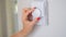Woman& x27;s hand regulating the temperature of central heating of house on thermostat