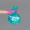 A woman`s hand in a rubber glove holds a transparent green garbage bag with empty plastic bottles.