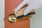 A woman`s hand in a rubber glove wipes the door handle with a sponge. Topic disinfection of door handles in an apartment, office d