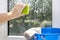 Woman`s hand rubs a soapy window with a sponge