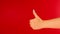 Woman& x27;s hand showing thumb up on red background with space for text. Unrecognizable person showing gesture of like.