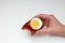 Woman`s hand with a smoked rye bread sandwich with half boiled egg with tomato sauce on a white background