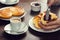 Woman\'s Hand Spreads Preserves on a Croissant Roll in a Cafe