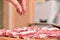 A woman`s hand sprinkles spices on raw pork meat. Seasoning for meat. Close-up