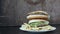 A woman`s hand takes a burger from a large mountain of three delicious juicy burgers with lettuce leaves and cheese