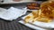 Woman`s hand takes a burger, next to the tray are roasted chicken wings and French fries. Fast food restaurant