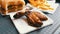 Woman`s hand takes fried chicken wings, alongside on a tray lies a bitten burger and French fries. Fast food restaurant