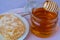 a woman\\\'s hand takes honey on a wooden stick from a full jar of honey with honeycombs on a plate
