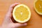 A woman`s hand takes a slice of organic fresh yellow lemon on a wooden cutting board. Slices of lemon on a board on a green