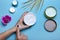 Woman`s hand takes some cream from a jar. Moisturizing cream in woman`s hands on blue background