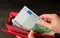 Woman`s hand taking Euro banknotes from the red wallet