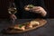 Woman`s hand taking one bruschetta. Appetizers with tomato, mozzarella, pesto, salmon and roast beef lay on wooden board. A glass