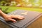 Woman`s hand touching the black stone grave at cemetery with orange sunlight flare