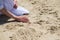 Woman`s hand touching sand at the shore of the sea - concept of native place.