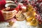 A woman`s hand in a warm sweater holds a red mug with a hot drink on a table with Christmas decorations. New year`s atmosphere, ci