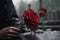 Woman\\\'s hand with a wedding ring puts a red rose on a black granite tombstone. Rain. Loss of a loved one