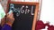 a woman's hand writes the words boy and girl in chalk on the board.