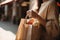 woman's hands carefully hold a craft paper bag with groceries