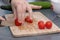 Woman`s hands cutting tomato, behind fresh vegetables