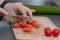 Woman`s hands cutting tomato, behind fresh vegetables