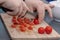 Woman`s hands cutting tomato, behind fresh vegetables