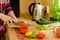 Woman\'s hands cutting tomato on the kitchen, other fresh vegetab