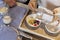 Woman& x27;s hands emptying granola into a bowl with yogurt while preparing breakfast with her husband