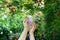 Woman`s hands hold face tonic bottle on a flowering natural background