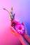 Woman`s hands hold pink eustoma flower in neon ultraviolet light. Beauty wallpaper