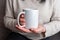 Woman\'s hands hold a pristine white mug, providing a perfect canvas