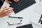 Woman`s hands holding black colored notepad that lying on the table