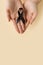 The woman & x27;s hands are holding black Ribbon for symbol Melanoma and skin cancer. Narcolepsy, Primary Biliary