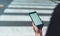 Woman`s hands holding close up mobile phone with blank white screen in city on background crosswalk city