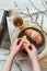 Woman`s hands holding croissant and a cup of tea on a white table. Shot from above