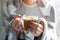 Woman`s hands holding hot steaming drink. Female covered in thro