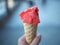 Woman`s hands holding melting strawberry ice cream waffle cone i