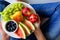 Woman`s hands holding plate with summer fruits: watermelon, blueberry,apples,pear and grape on white plate