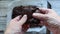 Woman`s hands holding and pulling apart a gooey fresh chocolate brownie