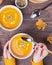 Woman`s hands holding table sppoon near the bowl of delecious homemade pumpkin soup