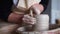 Woman`s hands making ceramic pot of wet clay in craft workshop