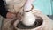 Woman`s hands making ceramic pot of wet clay in craft workshop