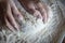 Woman`s hands with manicured nails work with dough in the kitchen